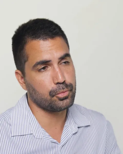 Portrait d'un homme en chemise rayée qui regarde hors cadre, sur fond blanc